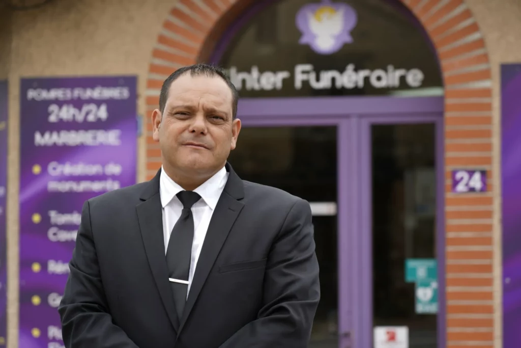 Conseiller funéraire en costume devant la devanture d'Inter Funéraire